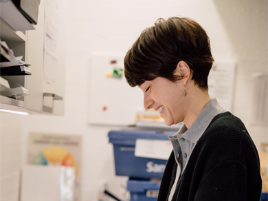 Apothekenmitarbeiterin arbeitet im Backoffice-Bereich der Medardus Apotheke, Regale und Ablagen im Hintergrund.