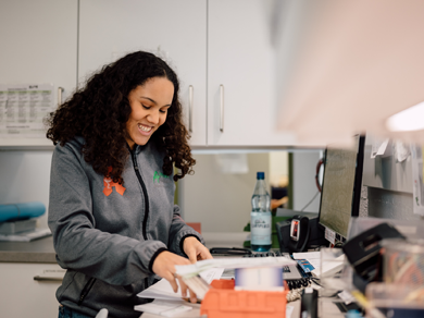 Mitarbeiterin der Medardus Apotheke sortiert Unterlagen am Arbeitsplatz mit Computer und Medikamenten.